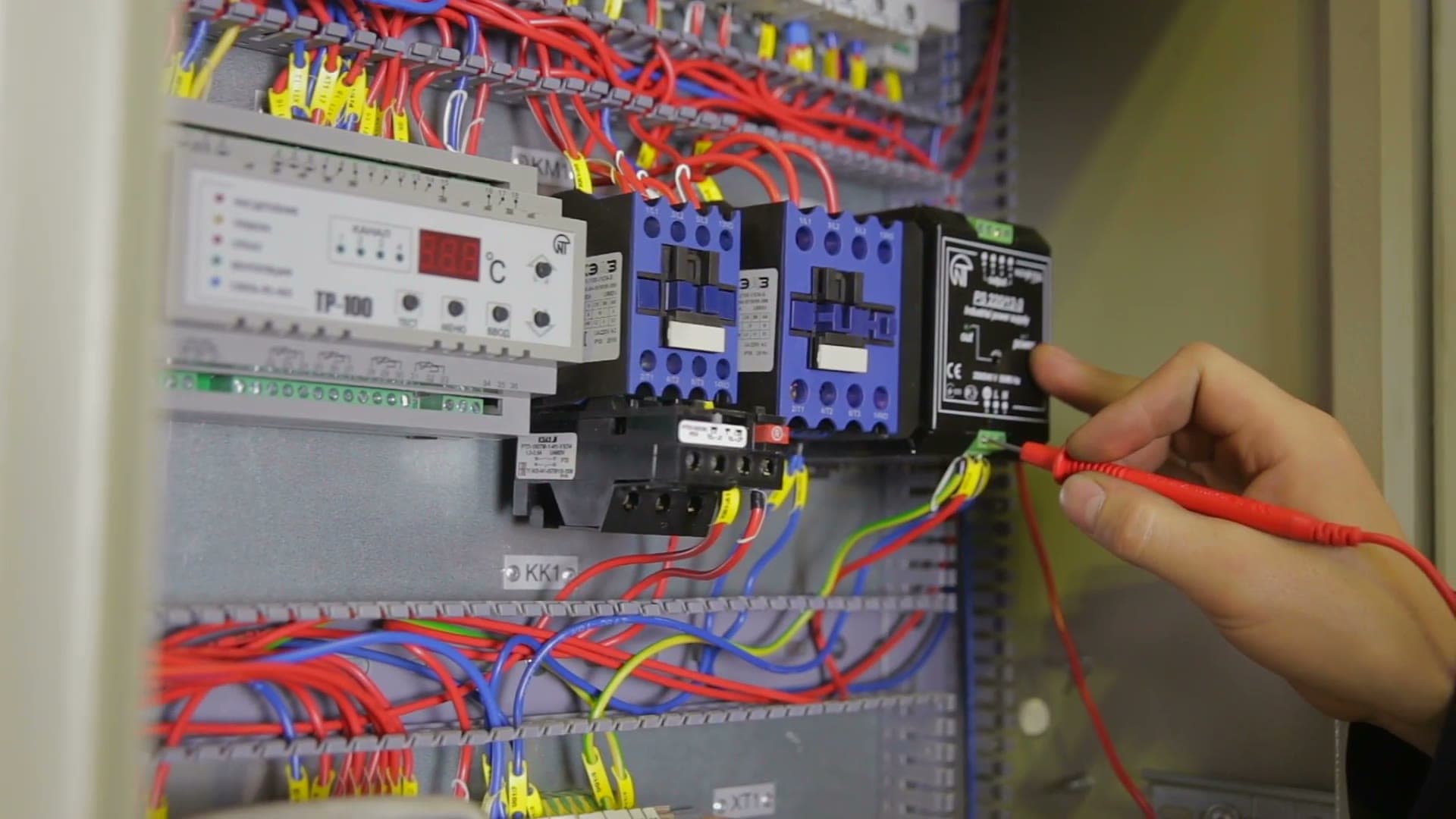 A licensed Power Amp electrician testing a switchboard with a multimeter